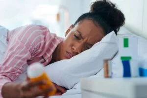 a woman waking up holding a pill bottle