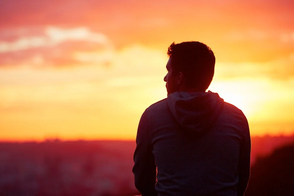 a man staring out during the sunset