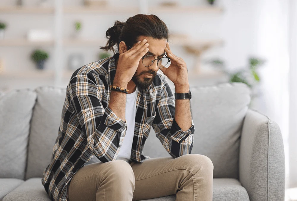 a man with hands on head sitting on couch