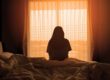 woman sitting on bed wondering how long heroin withdrawal lasts