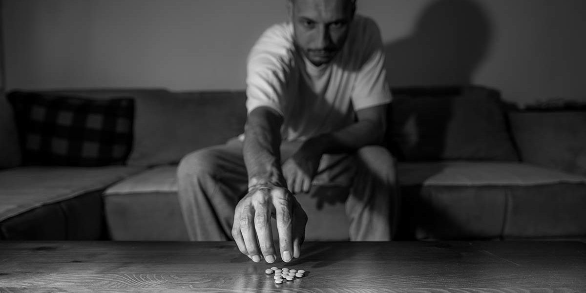 man reaching for pills because of his psychological dependence