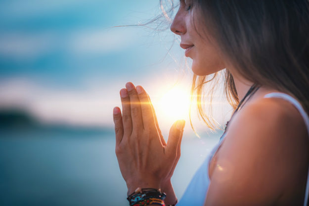 woman making prayer hands outside learning Can Mindfulness Meditation Work for Addiction