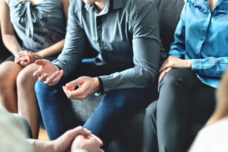 Individuals sitting together in a therapeutic setting discussing benzodiazepine addiction treatment