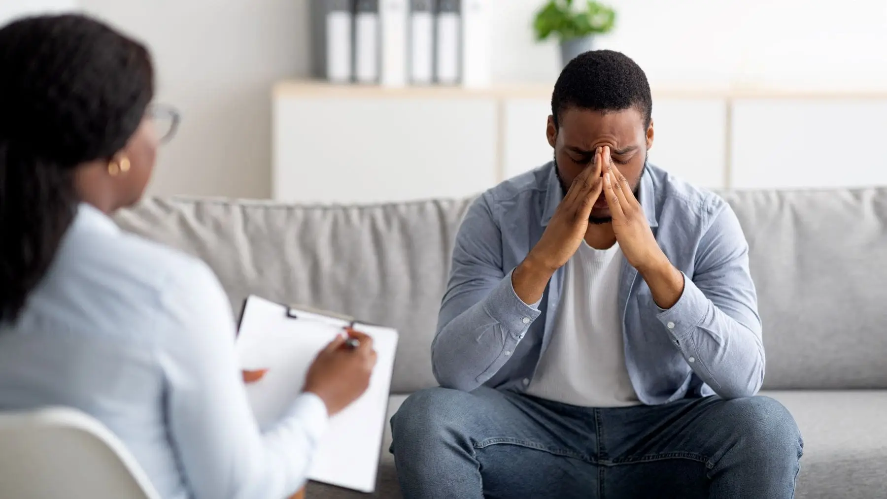 a man sits with his hands pressed to his face, having a session with trauma therapists Los Angeles support