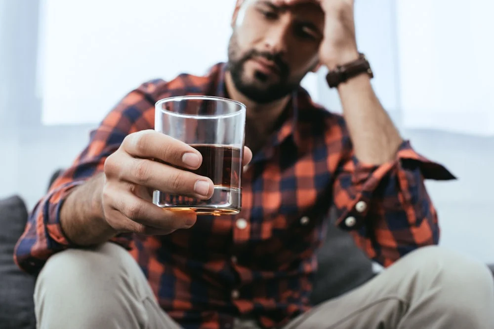 man holding a glass of whiskey during alcohol withdrawal