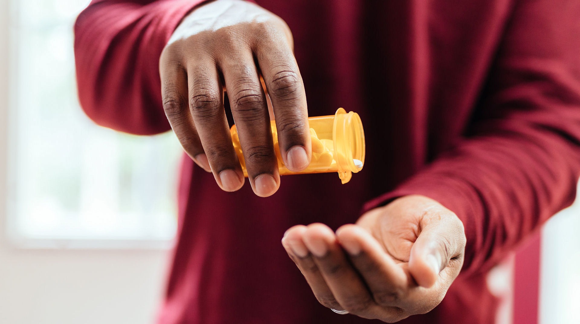 a-man-pouring-pills-into-hand