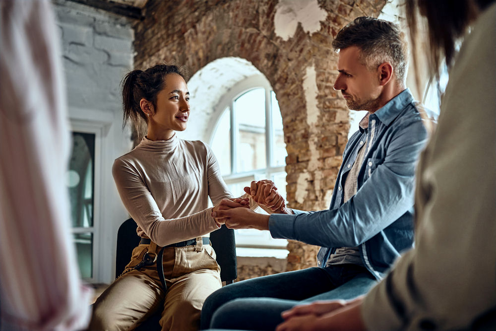 a-woman-and-man-holding-hands-in-therapy