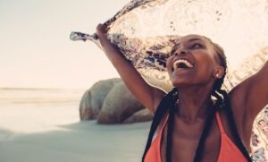 a-woman-smiling-and-happy-on-the-beach-showcasing-summer-self-care-on-mental-health