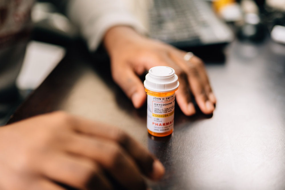 a-pair-of-hands-surrounding-a-pill-bottle-of-opioids