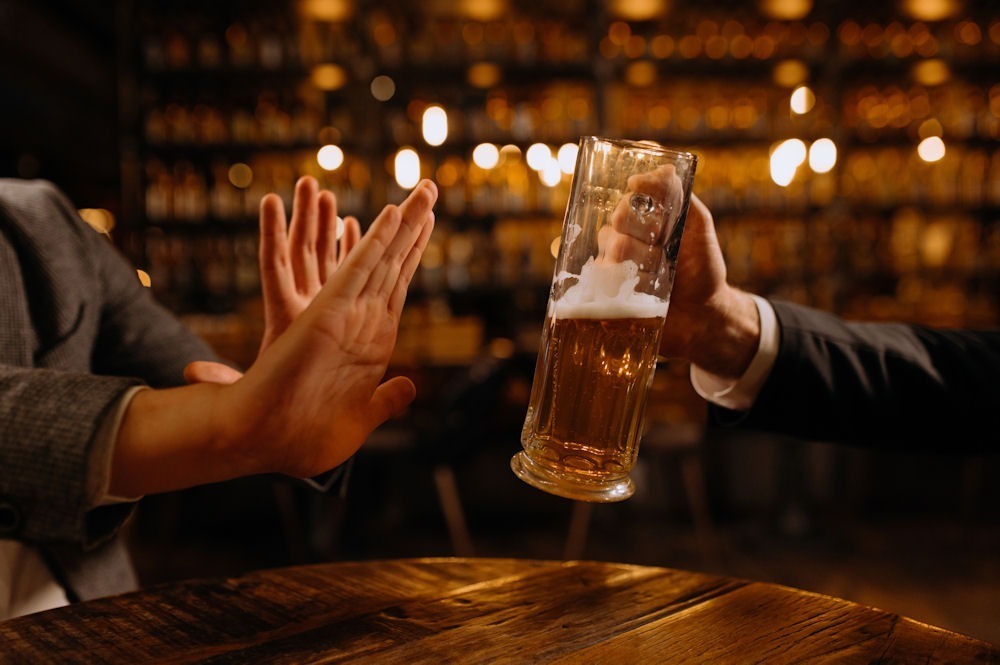 pair of hands turning down glass of alcohol