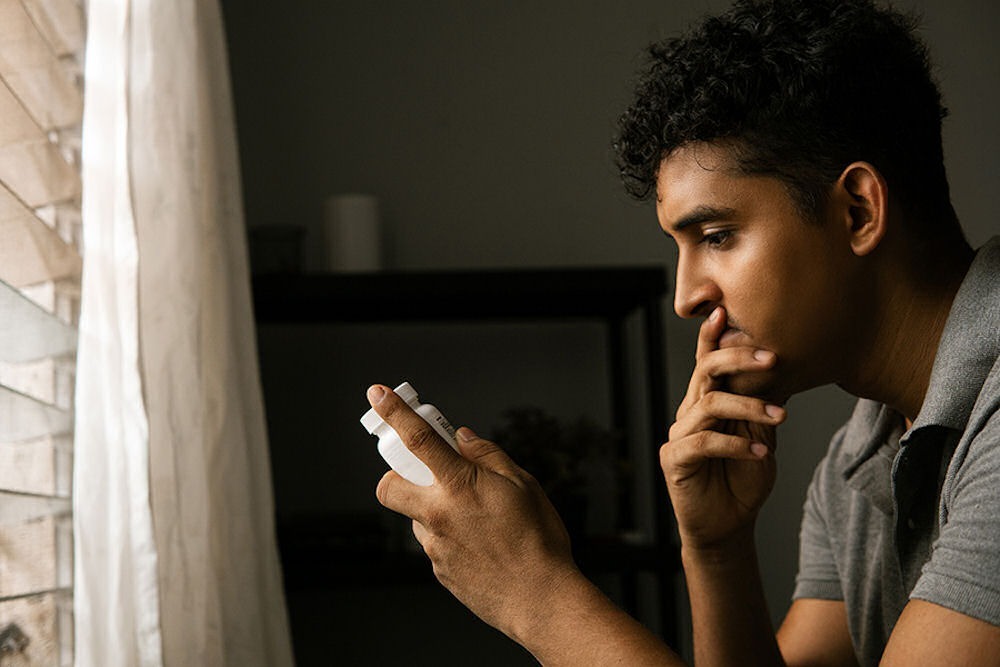 a man sitting in the room holding a pill bottle