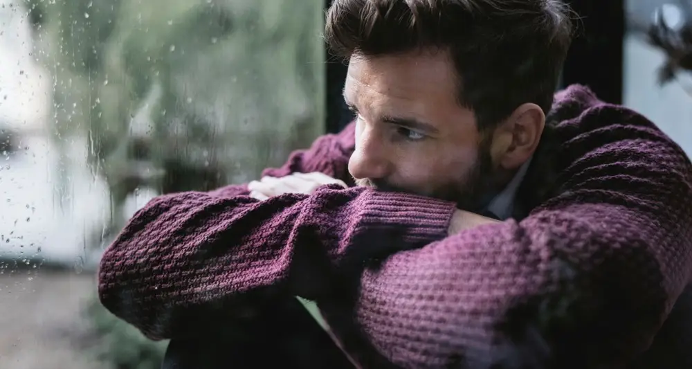 a sad man with ketamine addiction problem looking out the window