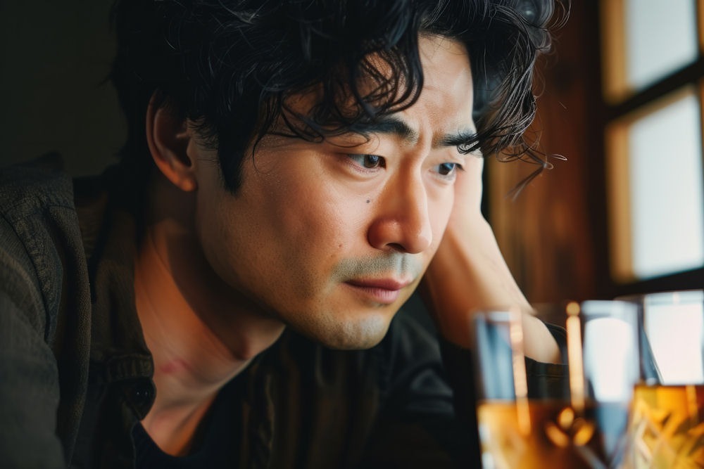 a man stressed in front of glass of beer