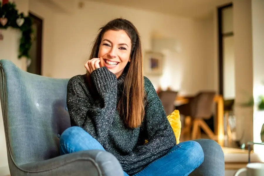 a woman smiling at home sitting on the chair