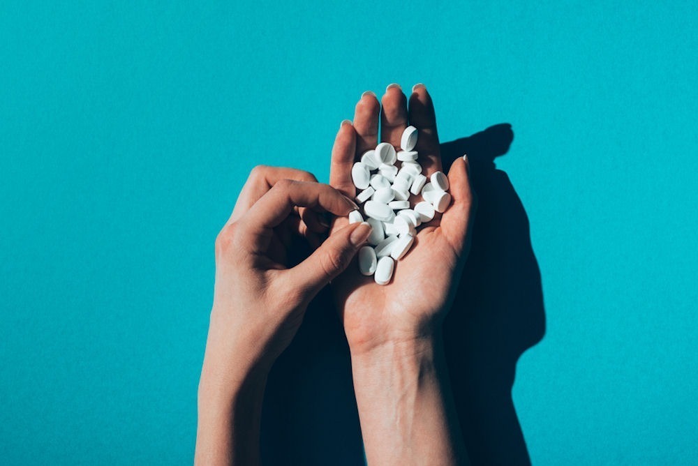 Handful of white pills representing the scale of the opioid epidemic