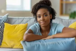 woman smiling on couch while packing essentials for rehab