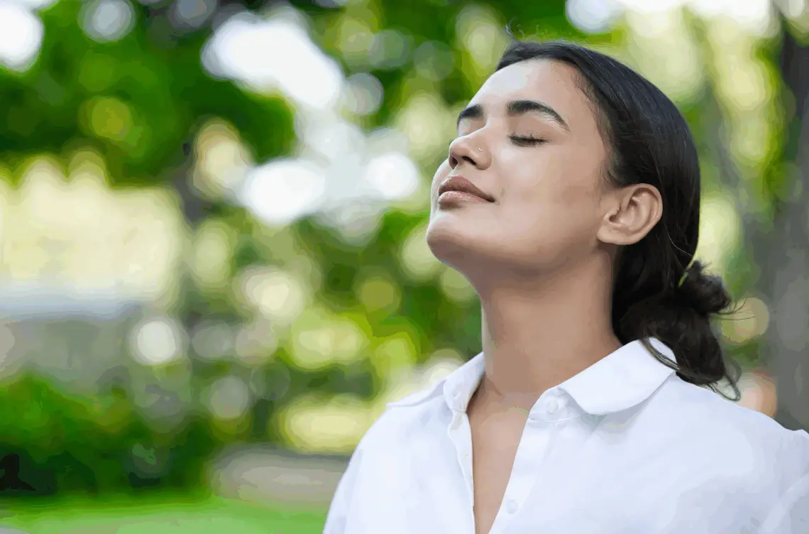 A woman with eyes closed in nature, showing the positivity of being sober