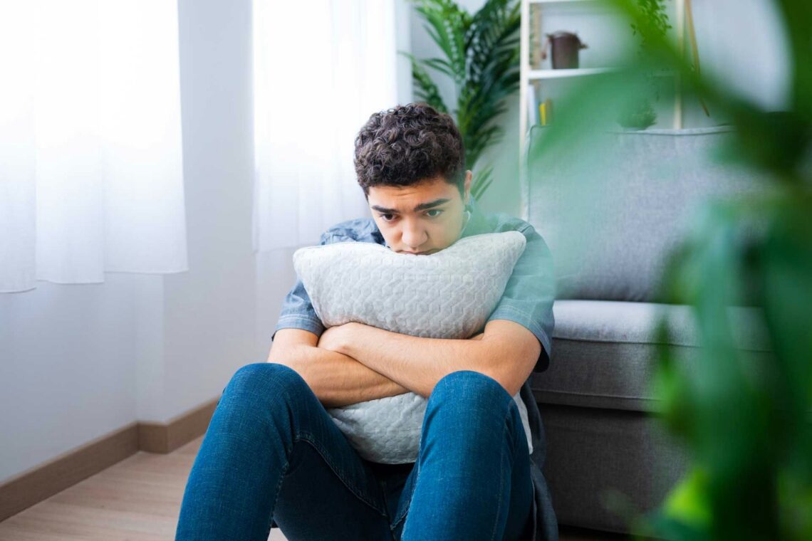 man sitting on the floor holding a pillow in fight-or-flight mode