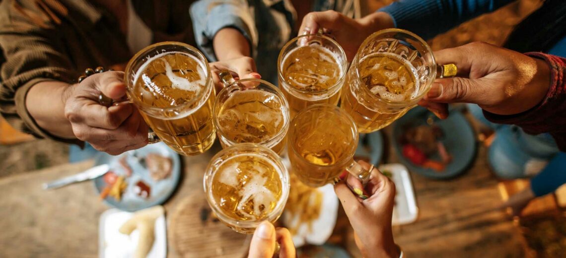 group of people raising beers in celebration, reflecting dry drunk behavior