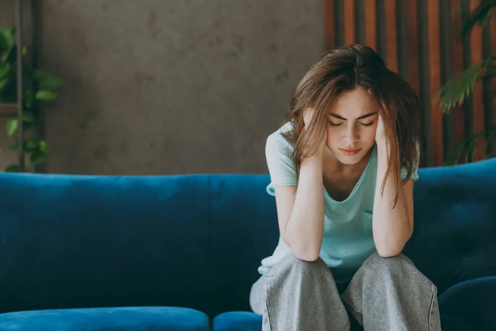a-woman-covering-her-ears-sitting-on-couch